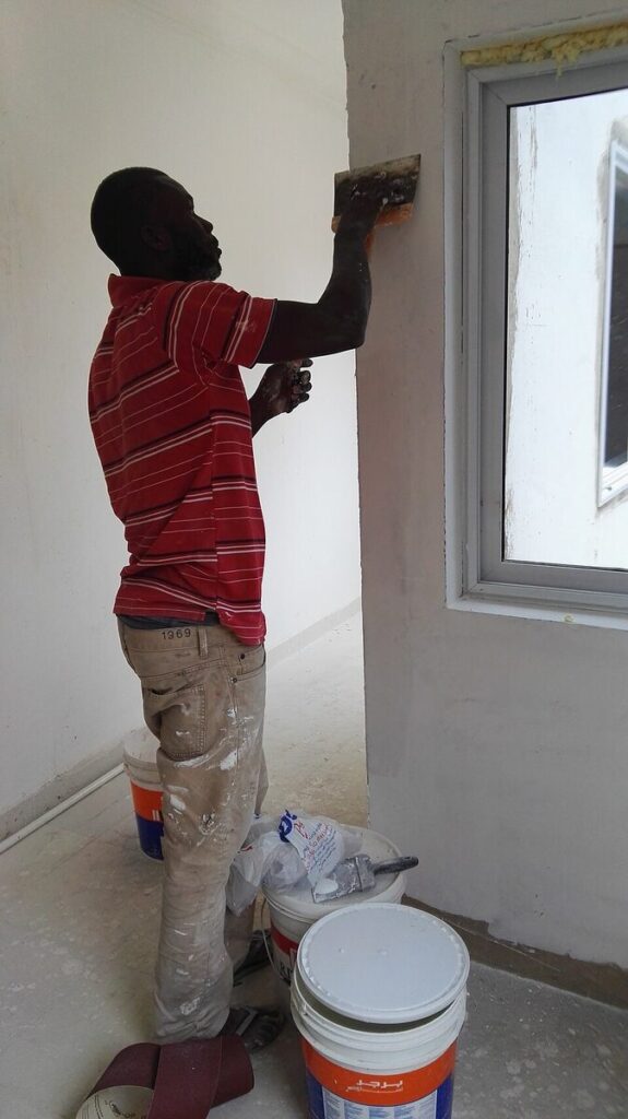 Trabajador enluciendo y preparando una pared antes de pintarla